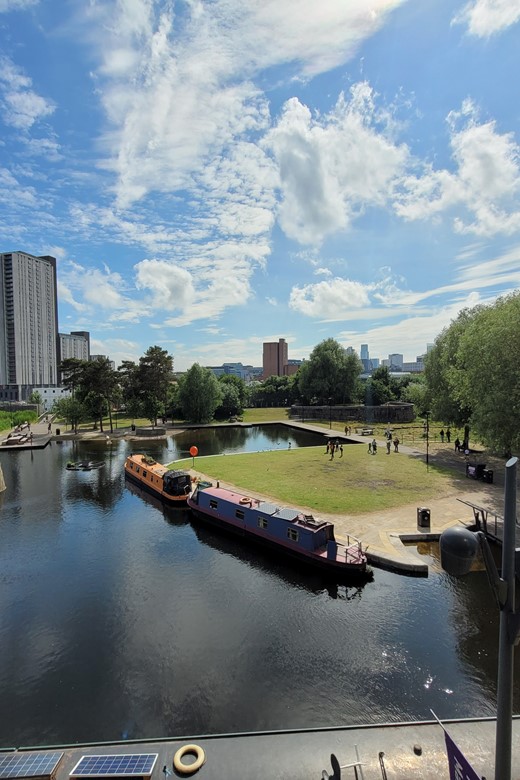 Views over Ancoats Marina with canal boats and Manchester City Centre